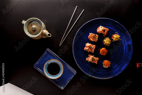 baked hot sushi rolls on a dark background. Hot fried Sushi Roll Sushi menu Set of sushi food with copy space Set of sushi with wasabi, soy sauce and teapot on black stone background