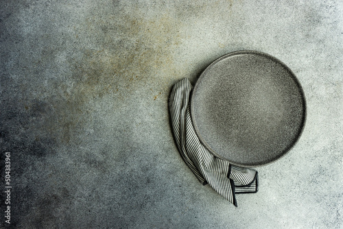 Overhead view of a grey ceramic plate and napkin on a table photo