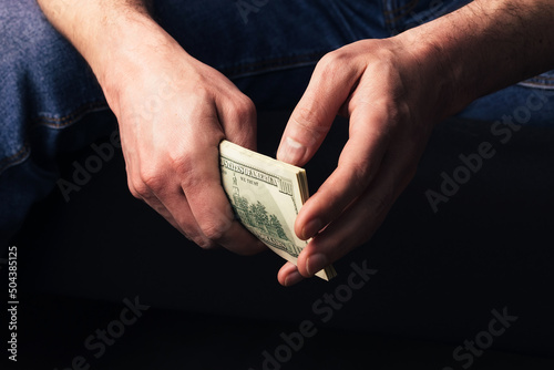 Male hands holding us hundred dollars banknotes. Man with american money closeup on black background