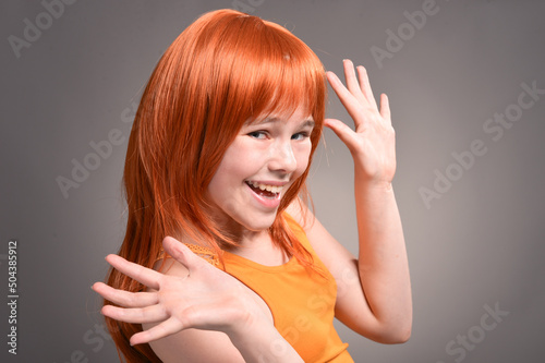 Portrait of cute girl with red hair posing in studio