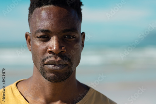 Close-up portrait of handsome serious confident african american young man at beach on sunny day