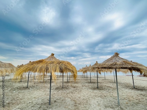 Straw beach umbrellas on a blue sky and sea background.Copy space  © Evis