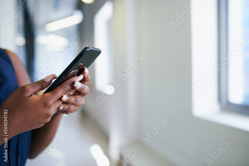 Close up of hands texting in office corridor