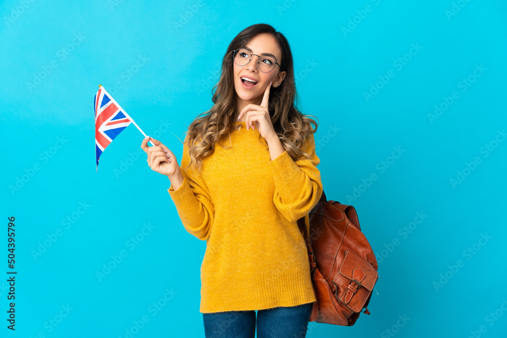 Young hispanic woman holding an United Kingdom flag isolated on blue background thinking an idea while looking up Young hispanic woman holding an United Kingdom flag isolated on blue background thinking an idea while looking up