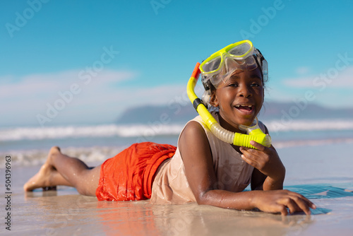 Obraz na plátně Portrait of happy african american wet girl wearing mask and snorkel lying at sh