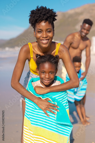 Portrait of smiling african american young parents wrapping wet children with towels at beach © wavebreak3