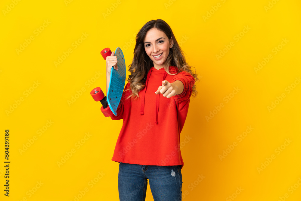 Young caucasian woman isolated on yellow background with a skate and pointing to the front Young caucasian woman isolated on yellow background with a skate and pointing to the front