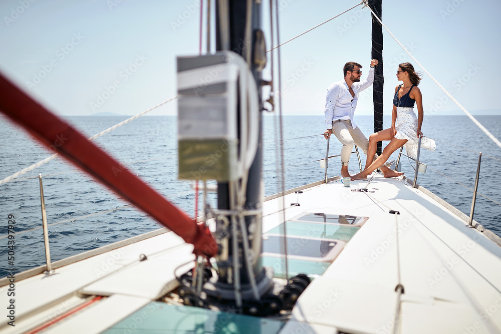 A young couple is chatting and posing for a photo on the bow of the yacht while enjoying a ride on the sea. Summer, sea, vacation, relationship A young couple is chatting and posing for a photo on the bow of the yacht while enjoying a ride on the sea. Summer, sea, vacation, relationship