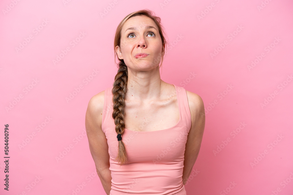 Young caucasian woman isolated on pink background and looking up Young caucasian woman isolated on pink background and looking up