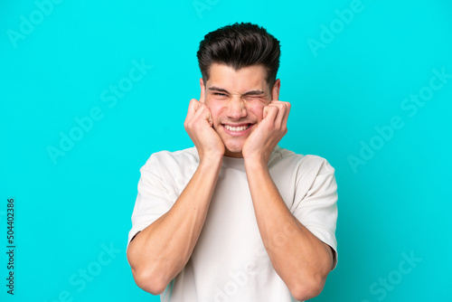 Young handsome caucasian man isolated on blue bakcground frustrated and covering ears