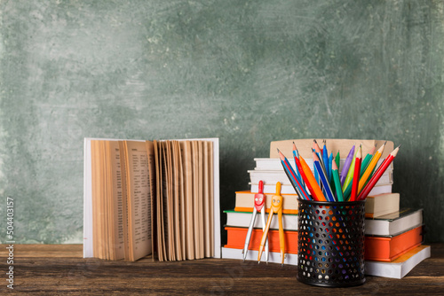 Stack of books and stationery on the background of the school board. Education and back to school concept.