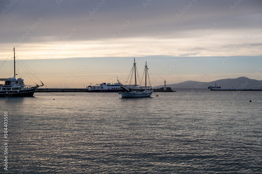 Cyclades, Greece. Moored boat at Mykonos island port, rippled sea, sky in the dusk background.