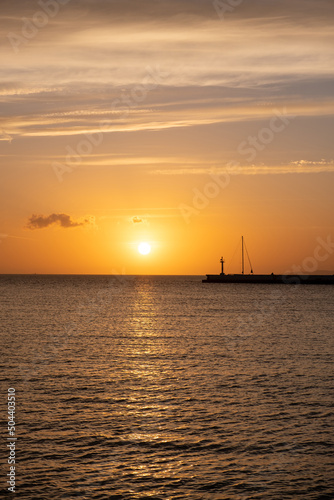 Sunset over Mykonos island, Cyclades, Greece. Lighthouse, orange yellow sky sparkle sea. Vertical © Rawf8