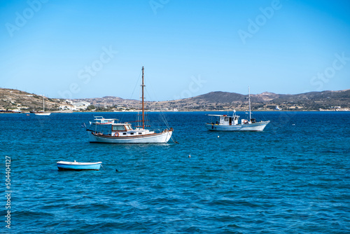 Milos Greek island, Cyclades. Fishing boat moored in open Aegean calm sea, blue sky background.