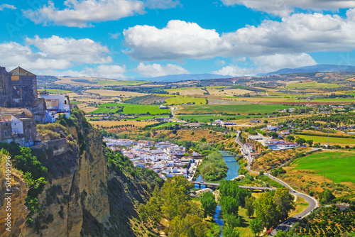 Beautiful andalusian landscape,  guadalete river, green rural valley, white village on mountain top, blue summer sky fluffy cumulus clouds - Arcos de la Frontera, Sierra de Cadiz Spain photo