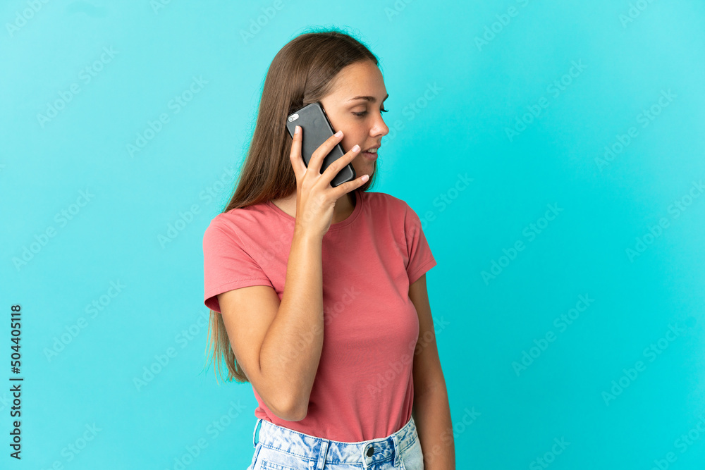 Young woman over isolated blue background keeping a conversation with the mobile phone with someone Young woman over isolated blue background keeping a conversation with the mobile phone with someone