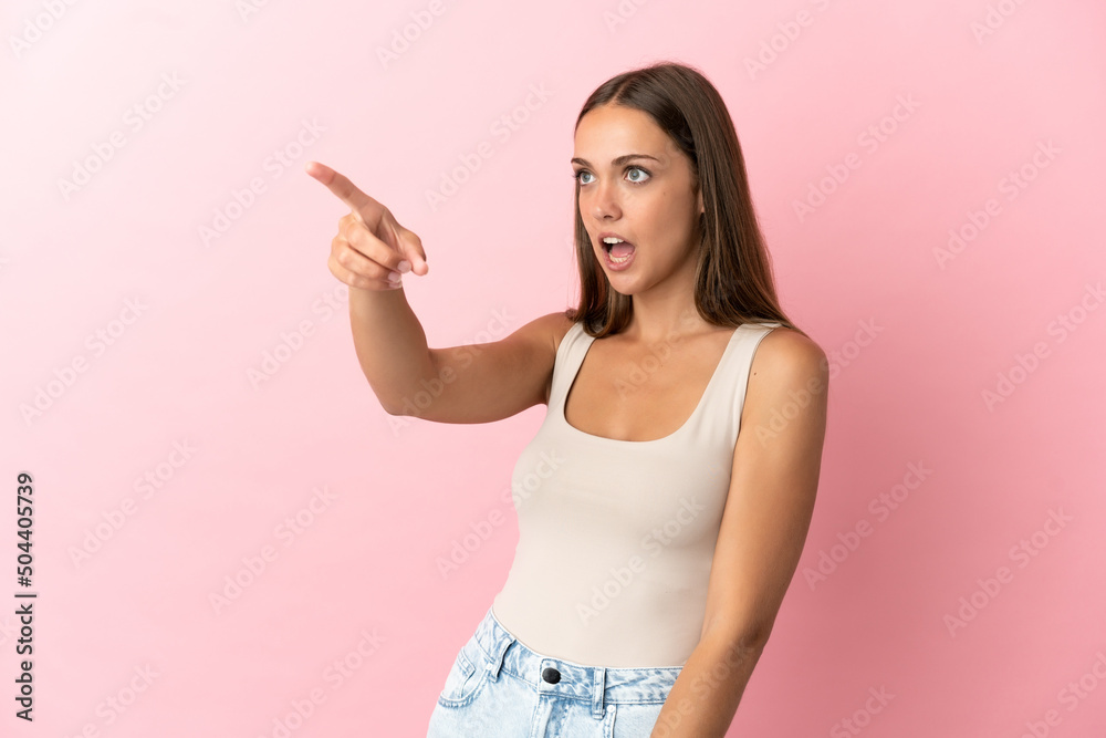 Young woman over isolated pink background pointing away Young woman over isolated pink background pointing away