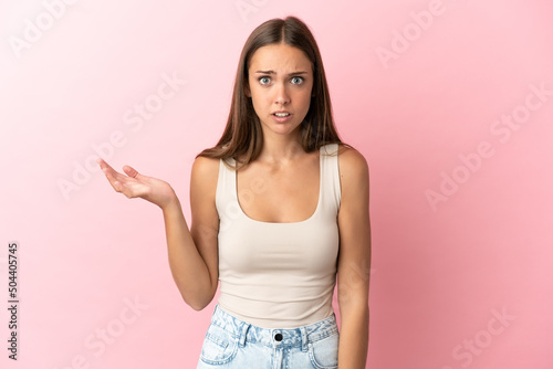 Young woman over isolated pink background making doubts gesture