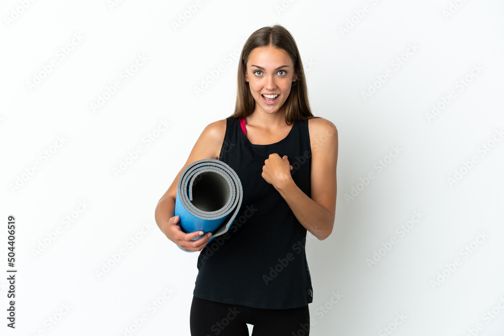 Sport woman going to yoga classes while holding a mat over isolated white background with surprise facial expression Sport woman going to yoga classes while holding a mat over isolated white background with surprise facial expression