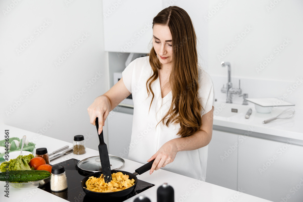 Girl cook an omelette on the pan 