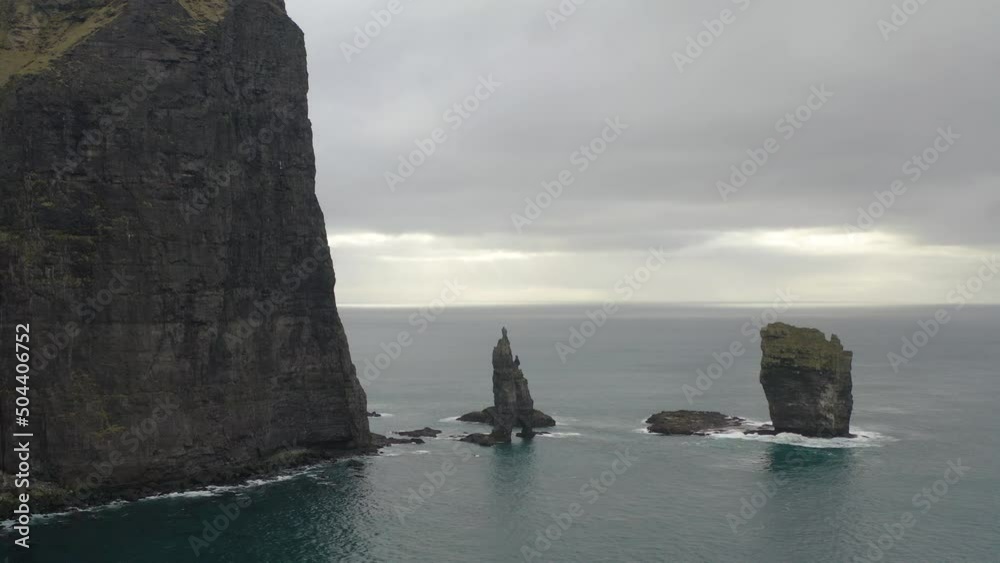 Risinn og Kerlingin Sea Stacks Against Gloomy Sky On The Northern Coast Of The Island Of Eysturoy In Faroe Islands. Aerial Drone Shot Risinn og Kerlingin Sea Stacks Against Gloomy Sky On The Northern Coast Of The Island Of Eysturoy In Faroe Islands. Aerial Drone Shot