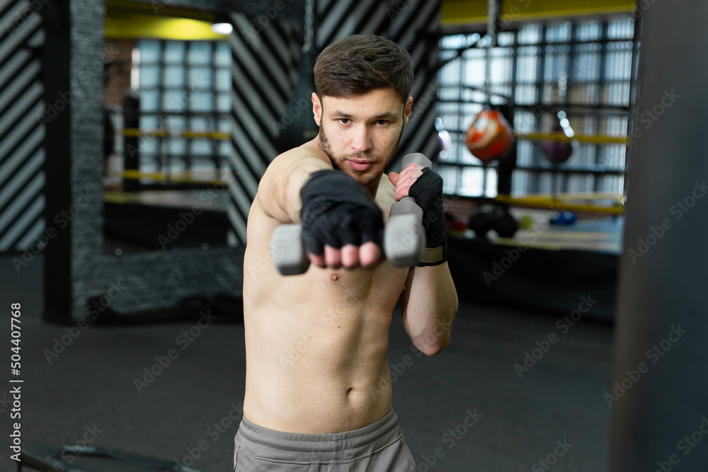 Kickboxer does a circular workout with dumbbells in the gym Kickboxer does a circular workout with dumbbells in the gym