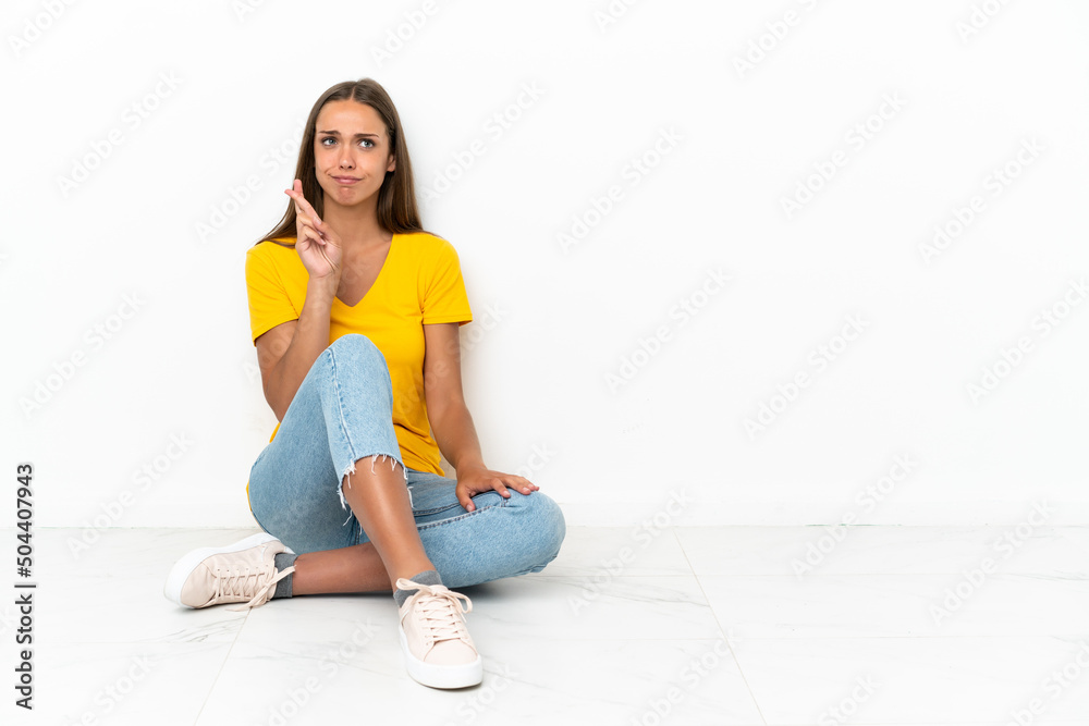 Young girl sitting on the floor with fingers crossing and wishing the best Young girl sitting on the floor with fingers crossing and wishing the best