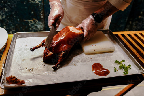 Chinese cook prepares Peking Roast Duck. Peking Duck is a famous duck dish from Beijing that has been prepared since the imperial era, and is now considered one of China's national foods. photo
