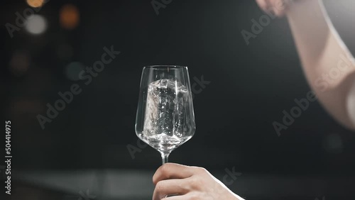 Professional bartender is putting ice in a glass
