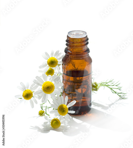 Cosmetic oil or perfume or drugs in brown glass with chamomile flowers.