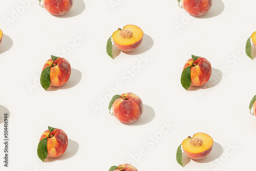 Fototapeta Naklejka Na Ścianę i Meble -  Summer fruit texture made of whole and halved peaches with stones and leaves on isolated pastel beige background. Minimal decorative pattern. Sun and shadows. Plant based raw organic food concept.