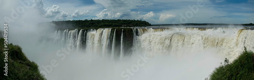 Panoramic view of many majestic powerful water cascades with mist and reflection of blue sky with clouds.