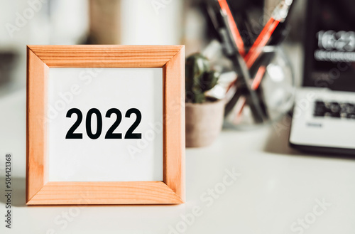 Office desk with office tools and a photo frame with 2022 numbers inside