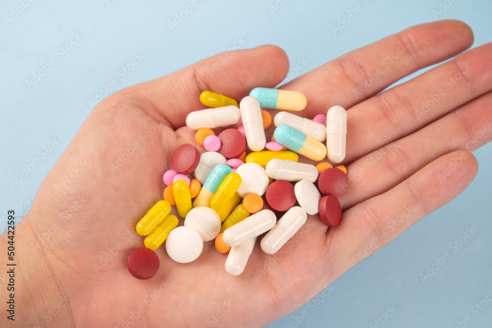 Man holding variety of medicine pills, capsules and tablets in his hands. A handful of pills. Immune system vitamins and supplemets. Man's health concept. Selective focus - obrazy, fototapety, plakaty 