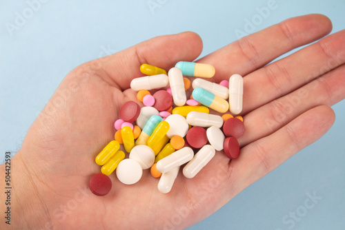 Man holding variety of medicine pills, capsules and tablets in his hands. A handful of pills. Immune system vitamins and supplemets. Man's health concept. Selective focus photo
