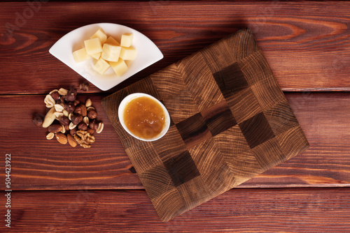 Cheese cut into pieces on a wooden board. Serving cheeses with honey and nuts.