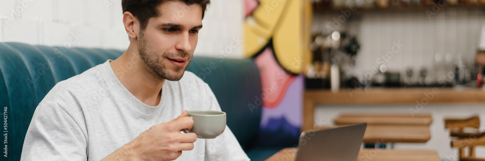 Smiling young man student sitting in cafe indoors Smiling young man student sitting in cafe indoors