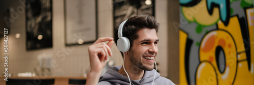 Smiling young casual man in earphones listening to music