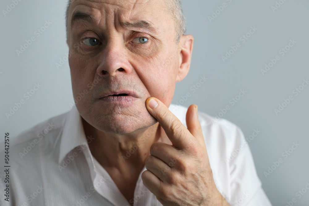 close-up charismatic mature man 60 years old applies aftershave on the face, critically examines face, skin, wrinkles, upset because age-related changes, midlife crisis, hair loss, selective focus close-up charismatic mature man 60 years old applies aftershave on the face, critically examines face, skin, wrinkles, upset because age-related changes, midlife crisis, hair loss, selective focus