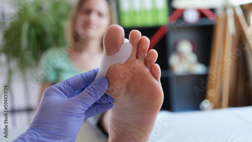 Doctor examines leg with hallux valgus deformity of first toe photo
