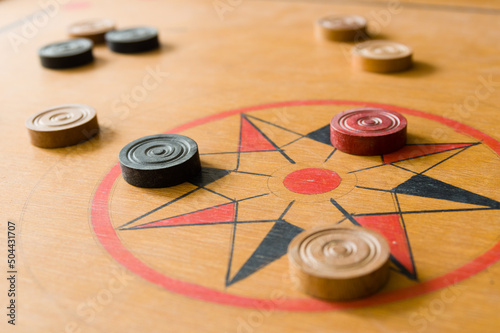 A game of carrom with scattered stones on the board around the center star