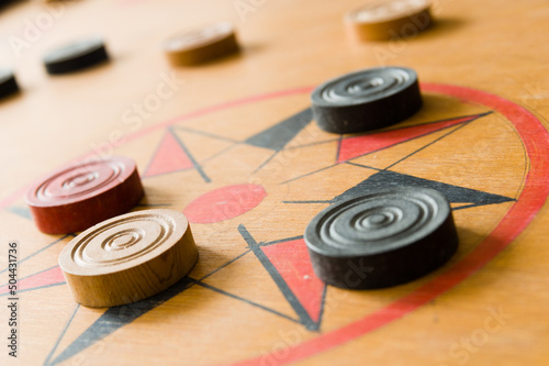 A game of carrom with scattered stones on the board around the center star