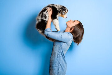 Handsome female with her Australian Berger puppy on studio blue background