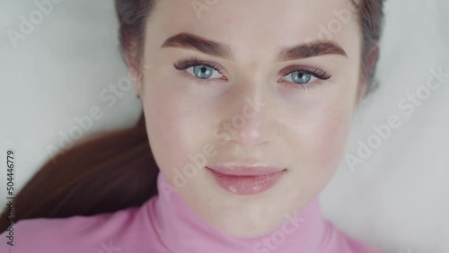 Beautiful young woman slowly opens her eyes after the eyelash extension procedure photo