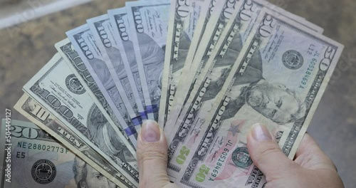 Dollars in female hands on background of wooden table. Woman counting 100 and 50 American dollar banknotes in arms. Lots of one hundred dollar bills. Banknotes on wooden table. Finance, economy, savin