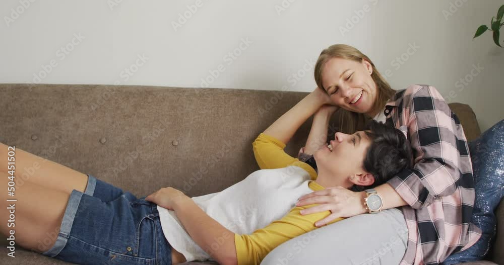 Caucasian woman lying on the lap of her wife on the couch at home