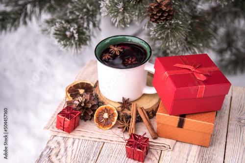 Top view of a cup with mulled wine spices and boxes with gifts on a wooden table.