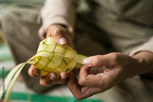 Weaving the coconut leaves making the ketupat, a traditional Malay cuisine during the Eid celebration. Selective focus points