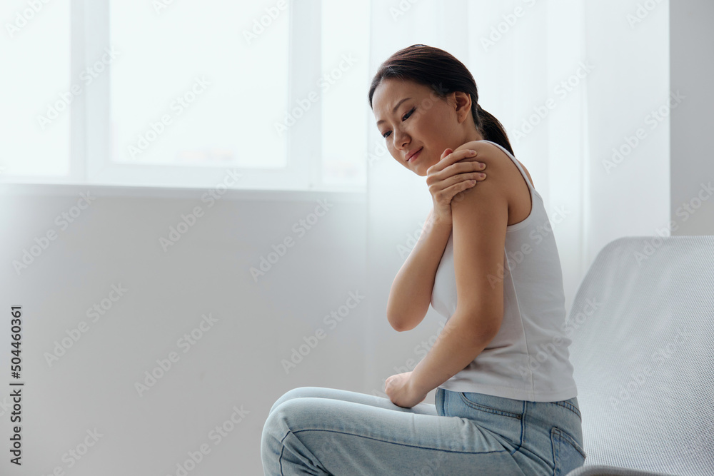 Suffering from neuralgia after sleeping in the wrong position tanned beautiful young Asian woman touching painful shoulder at home living room. Injuries Poor health Illness concept. Cool offer Banner Suffering from neuralgia after sleeping in the wrong position tanned beautiful young Asian woman touching painful shoulder at home living room. Injuries Poor health Illness concept. Cool offer Banner