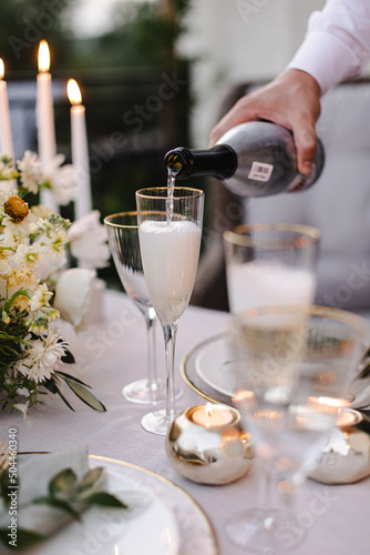 Banquet table is decorated with plates, cutlery, glasses and flower arrangements